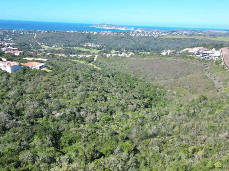 An aerial view of the vacant residential land, showcasing the surrounding coastal landscape, indigenous vegetation, and established residential estate.
