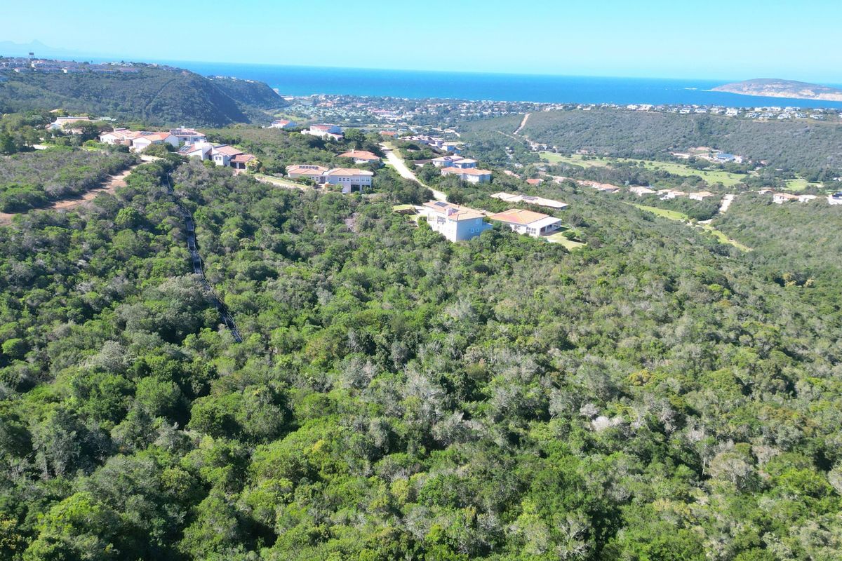 An aerial view of a residential estate nestled within a lush, green landscape, offering expansive views of the surrounding coastline and ocean.