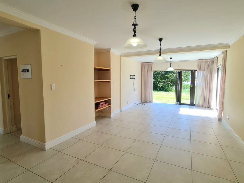 Spacious open-plan living area featuring neutral tiled flooring, built-in shelving, and large sliding glass doors providing direct access to the outdoor space.