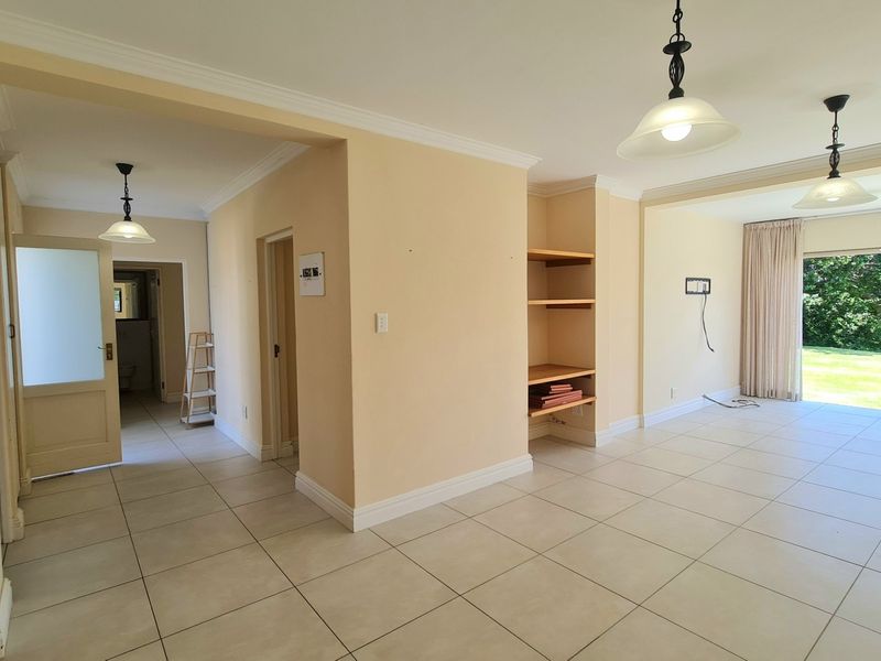 Spacious open-plan living area featuring neutral tiled flooring, built-in shelving, and large sliding glass doors providing access to the garden.
