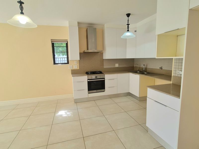 A clean, modern kitchen featuring white cabinetry, stainless steel appliances, tiled flooring, and a neutral backsplash, offering a functional and bright cooking space.