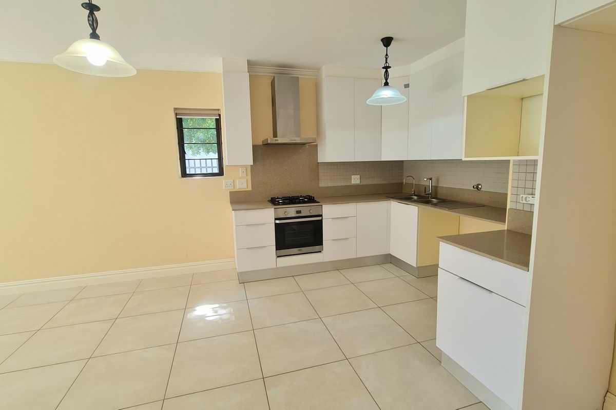 A clean, modern kitchen featuring white cabinetry, stainless steel appliances, tiled flooring, and a neutral backsplash, offering a functional and bright cooking space.