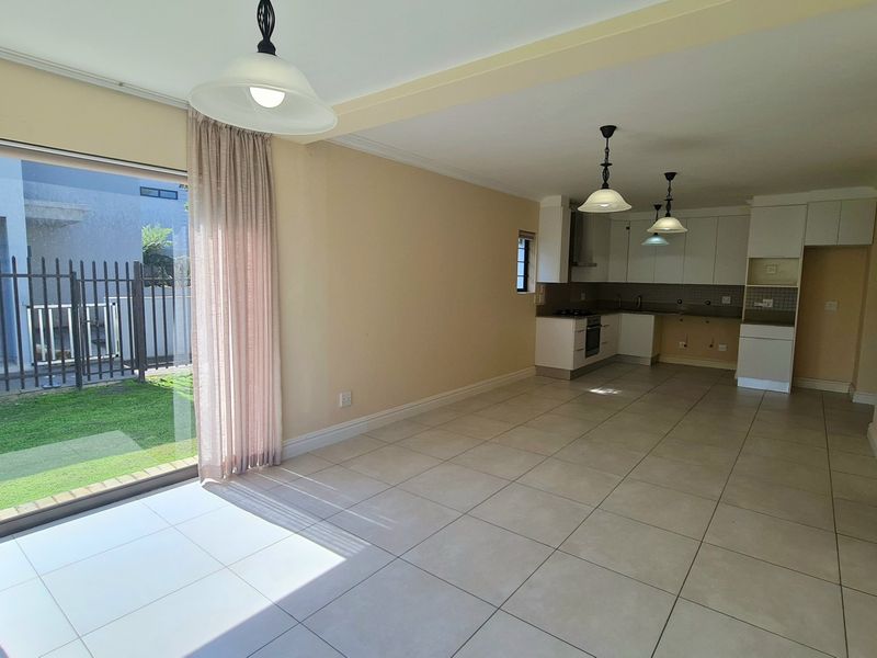 Spacious open-plan living and kitchen area featuring tiled floors, sliding doors to the garden, and a kitchen requiring minor cabinetry repairs.