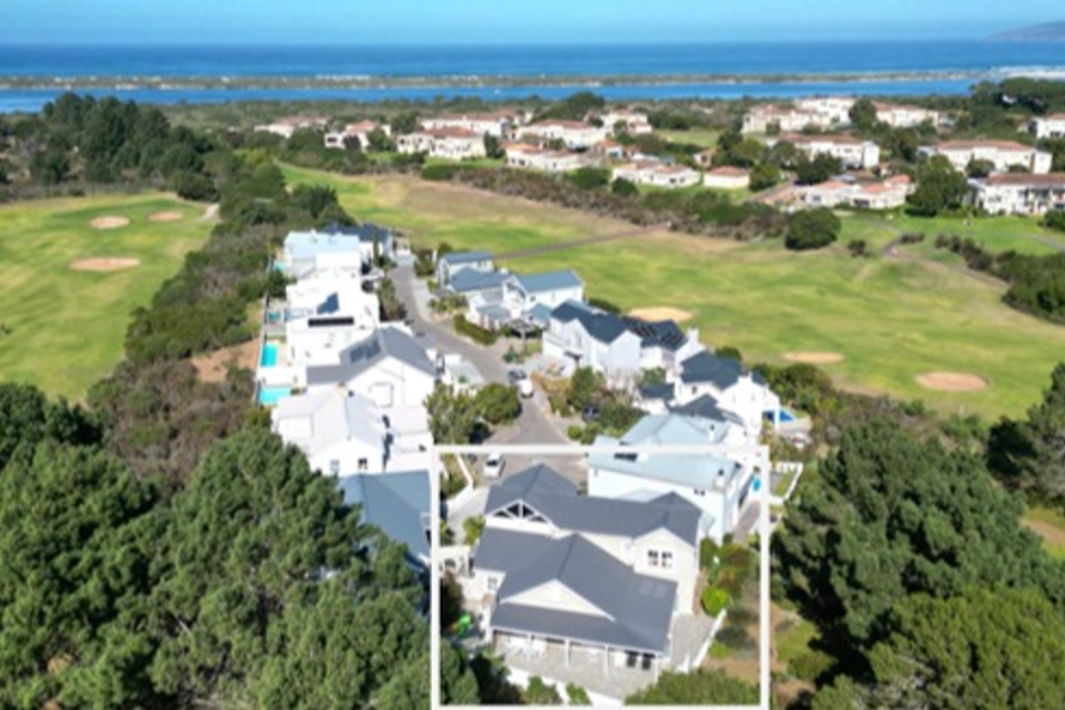Aerial view of the property highlighting its position within the estate, featuring a pitched roof, covered patio, and surrounding landscaped grounds.