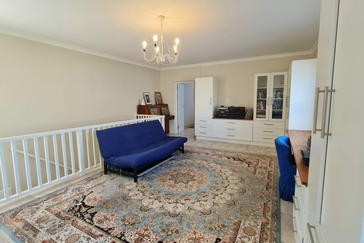 Spacious living area featuring built-in cabinetry, decorative chandelier lighting, and a staircase balustrade overlooking the lower level.