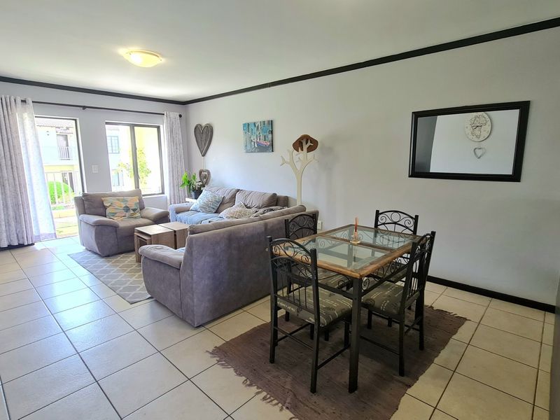 Open-plan living and dining area featuring neutral tiled flooring and a sliding glass door providing access to an outdoor balcony.