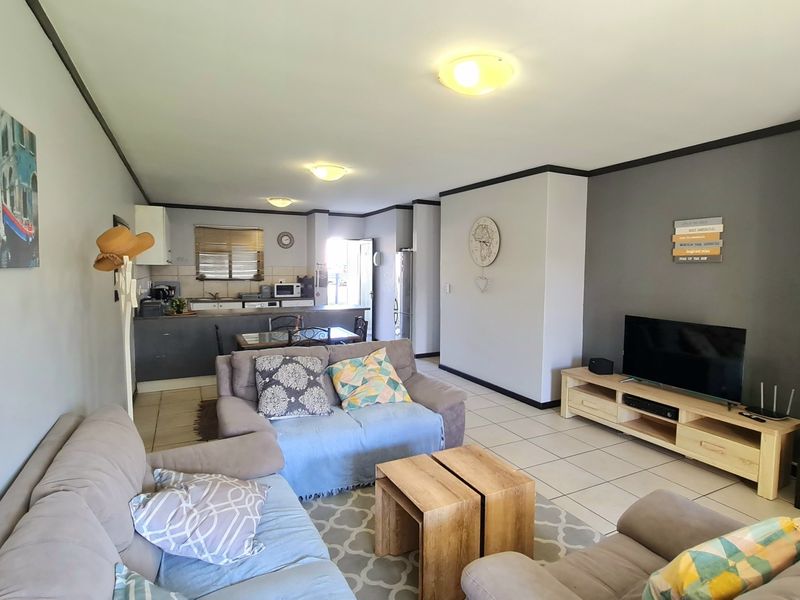 Open-plan living area featuring tiled flooring and a functional kitchen space with built-in cabinetry, creating a cohesive and versatile living environment.