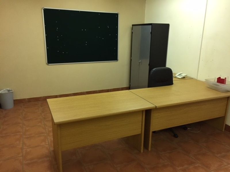 A functional office space featuring tiled flooring and a wall-mounted pin board, providing a practical environment for professional work.