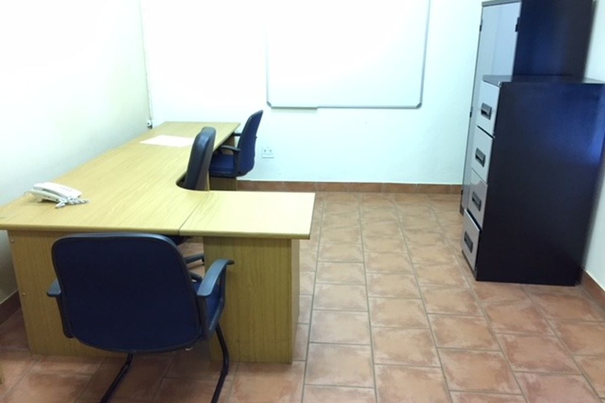 A functional office space featuring tiled flooring and a wall-mounted whiteboard, providing a practical environment for professional work.