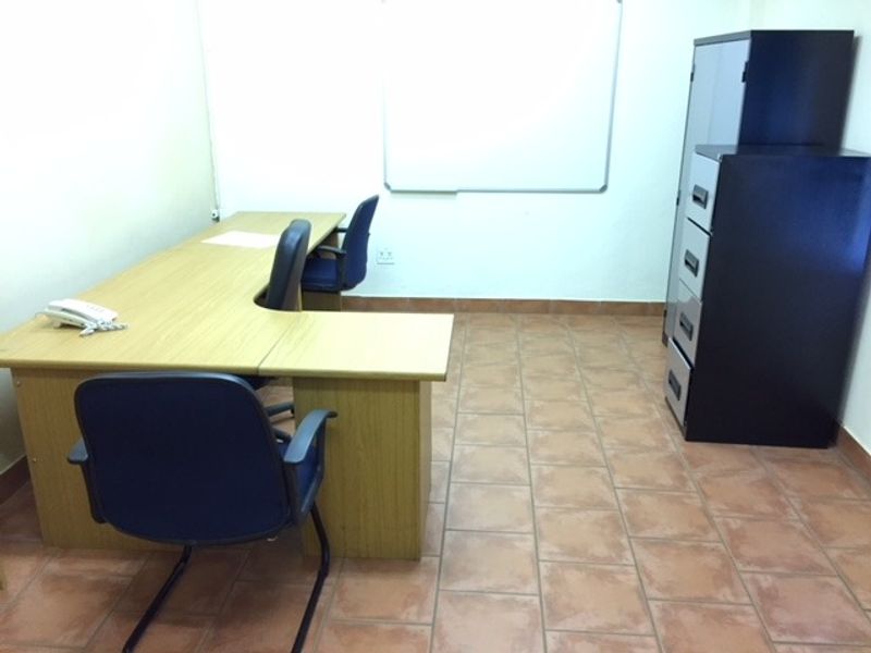 A functional office space featuring tiled flooring and a wall-mounted whiteboard, providing a practical environment for professional work.