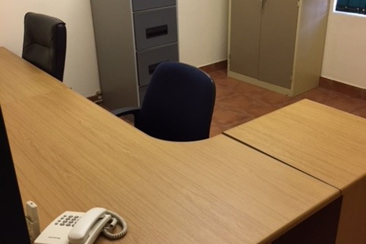 A functional office space featuring tiled flooring and a window, providing a practical environment for professional work.