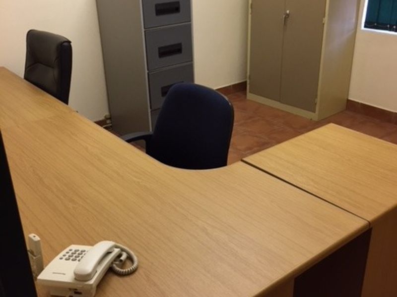 A functional office space featuring tiled flooring and a window, providing a practical environment for professional work.