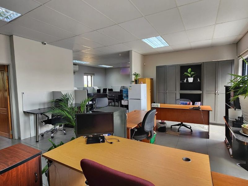 A functional open-plan office space featuring tiled flooring, recessed ceiling lighting, and integrated storage cabinetry, providing a practical workspace environment.