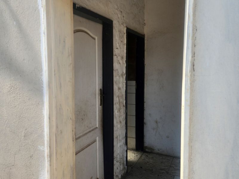 A narrow hallway area showing signs of wear, featuring internal doors and tiled flooring, requiring cosmetic refurbishment and paint.