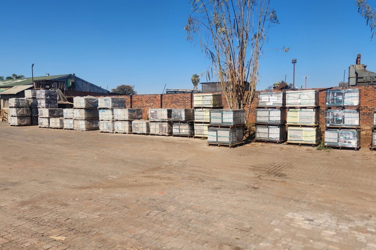Spacious industrial yard featuring a paved surface and a secure brick perimeter wall, suitable for storage or logistics operations.