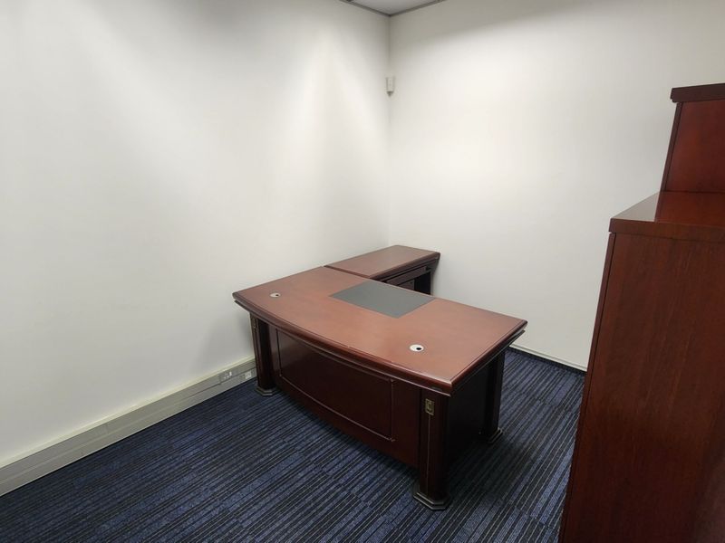 A functional office space featuring dark blue patterned carpet flooring and neutral white walls, suitable for a professional workspace.