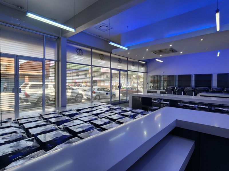 Modern retail space featuring a large service counter, extensive glass storefront windows, and integrated recessed lighting, suitable for a showroom or commercial display.