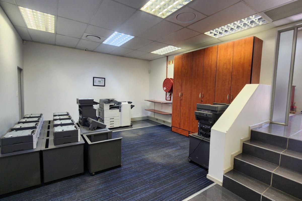 Functional office space featuring a suspended ceiling, built-in storage cabinetry, carpeted flooring, and direct access to a staircase.