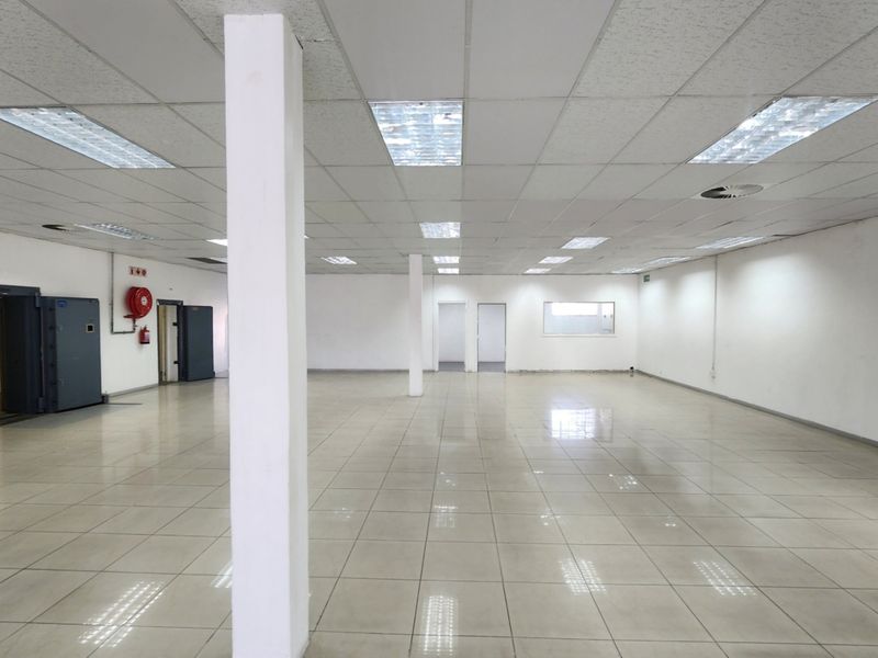 Spacious open-plan retail area featuring ceramic tiled flooring, suspended ceilings with recessed lighting, and a secure vault room.