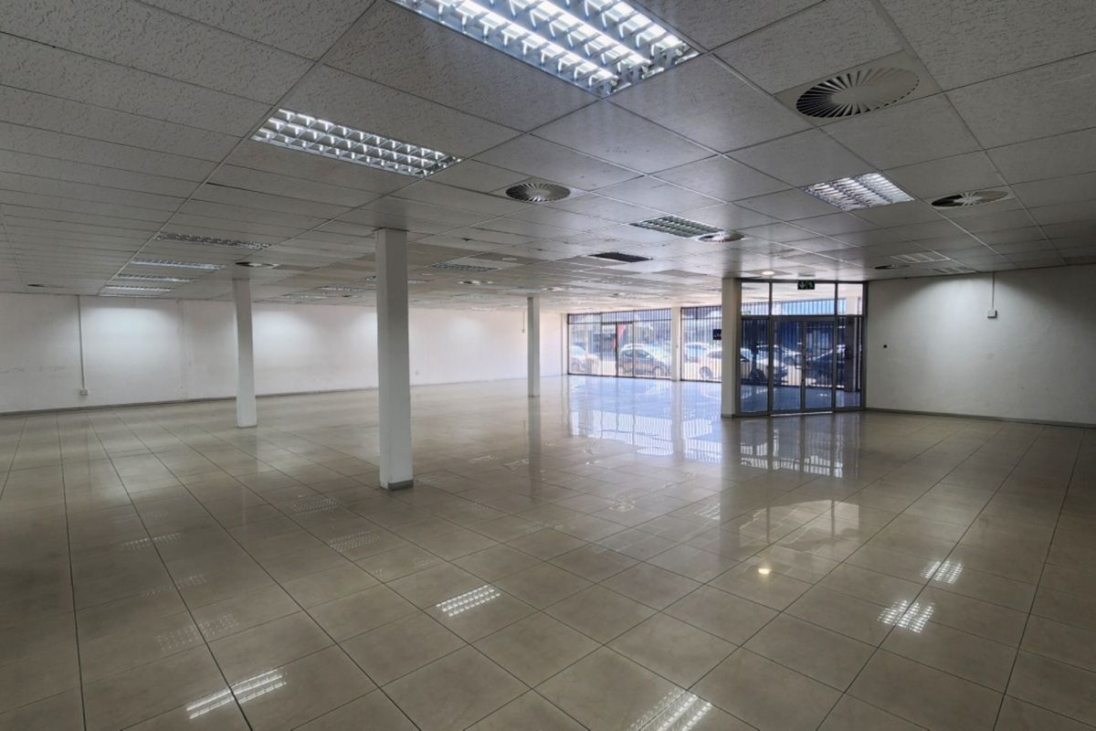 Spacious open-plan retail unit featuring ceramic tiled flooring, suspended ceilings with recessed lighting, and a prominent glass storefront entrance.