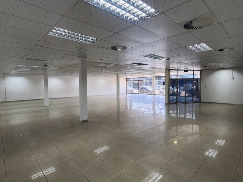 Spacious open-plan retail unit featuring ceramic tiled flooring, suspended ceilings with recessed lighting, and a prominent glass storefront entrance.