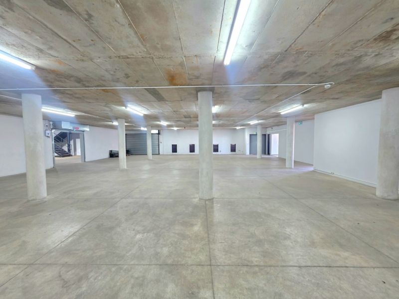 Spacious open-plan industrial utility area featuring exposed concrete ceilings, structural columns, and durable concrete flooring, suitable for storage or workshop use.