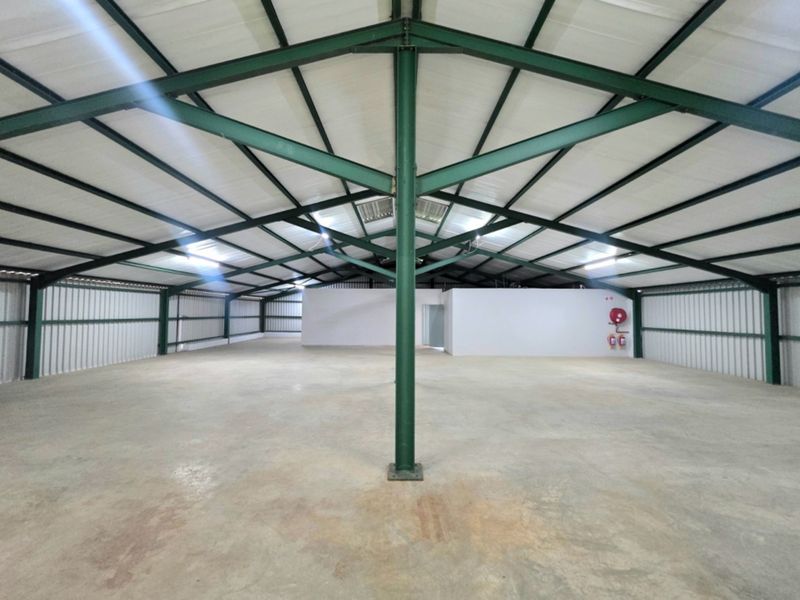 Spacious industrial warehouse unit featuring exposed steel truss roofing, concrete flooring, and corrugated metal wall cladding, suitable for storage or light manufacturing.