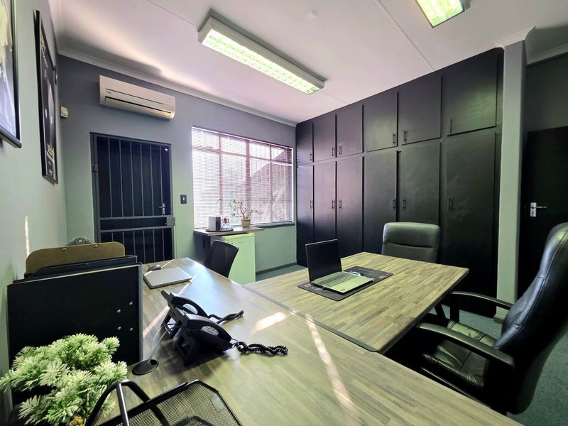 A professional office space featuring extensive built-in black cabinetry, air conditioning, and secure access, providing a functional and organized work environment.
