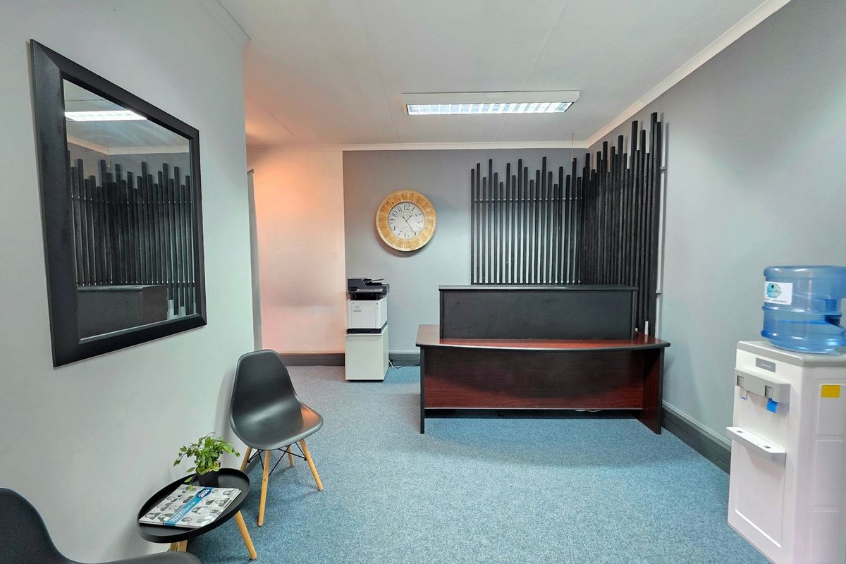 A professional office reception area featuring carpeted flooring, recessed fluorescent lighting, and decorative wall paneling.