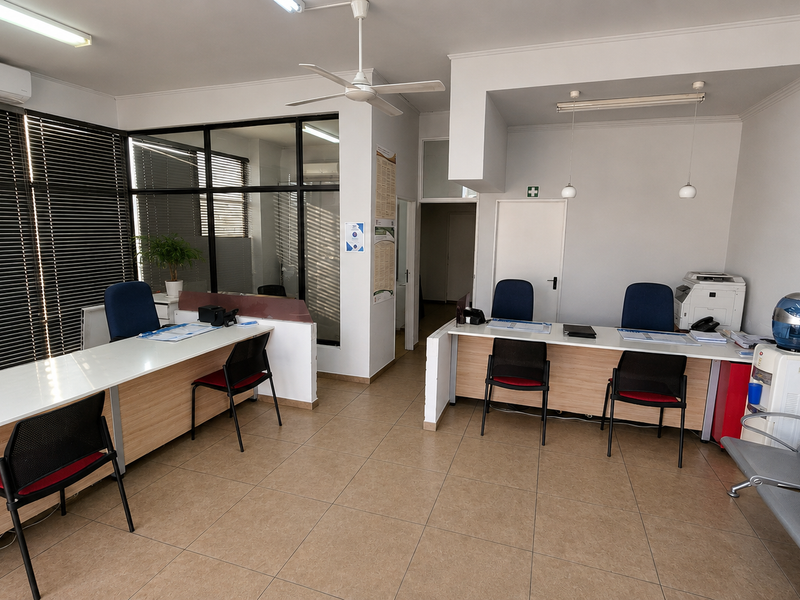 A functional office space featuring built-in desks, glass partitions, tiled flooring, and integrated climate control, suitable for a professional work environment.