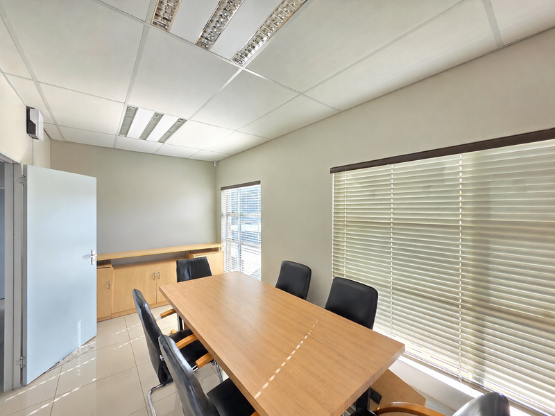 A professional office space featuring tiled flooring, suspended ceilings with recessed lighting, and large windows fitted with venetian blinds.