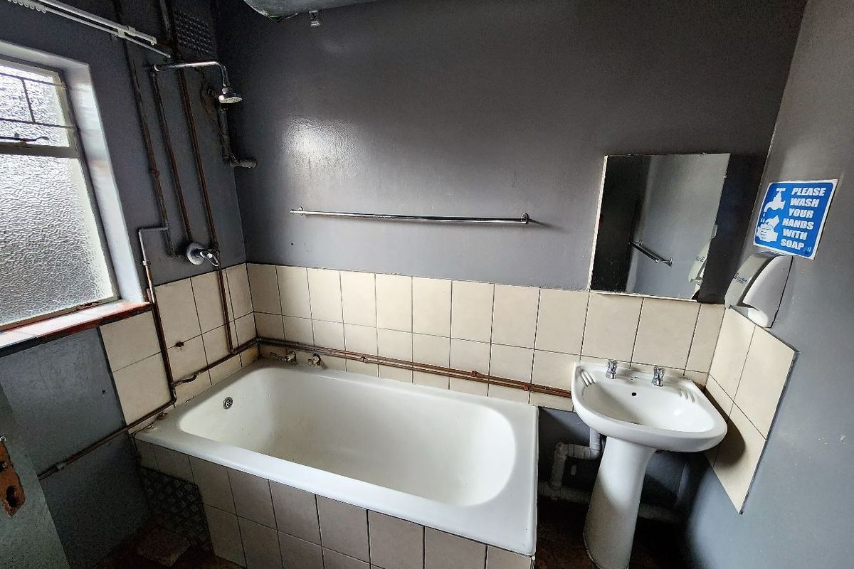 A dated bathroom featuring a standard bathtub, pedestal basin, and exposed plumbing, requiring modernization and cosmetic updates to improve functionality and aesthetic appeal.