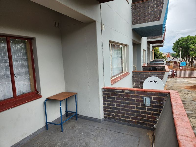 A functional apartment balcony featuring a brick balustrade and concrete flooring, providing an outdoor space with views of the surrounding complex.