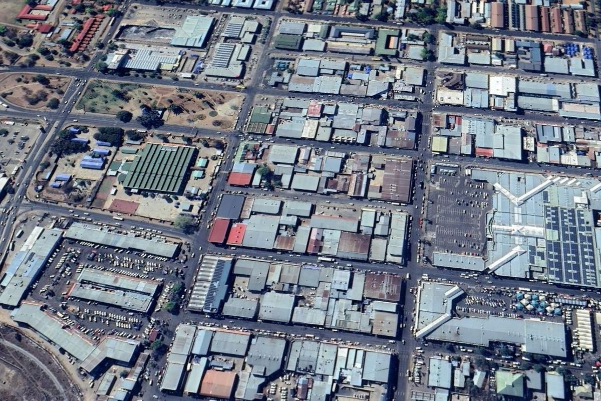 An aerial view of a dense commercial and industrial district featuring various warehouse structures, road networks, and large parking facilities.