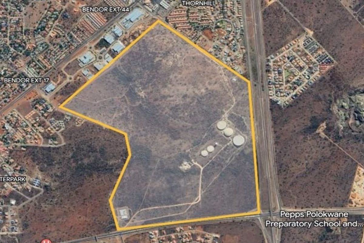 Aerial view of a large vacant commercial land parcel featuring existing water storage infrastructure, situated near residential developments and major road access.