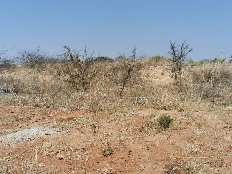A view of the vacant commercial land featuring natural dry vegetation and uneven terrain.