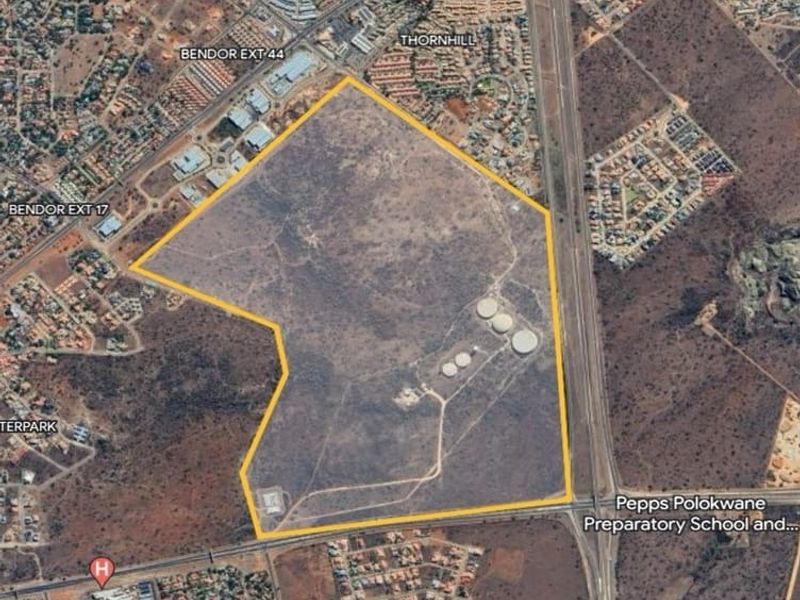 Aerial view of a large vacant commercial land parcel featuring existing water storage infrastructure, situated near residential developments and major road access.