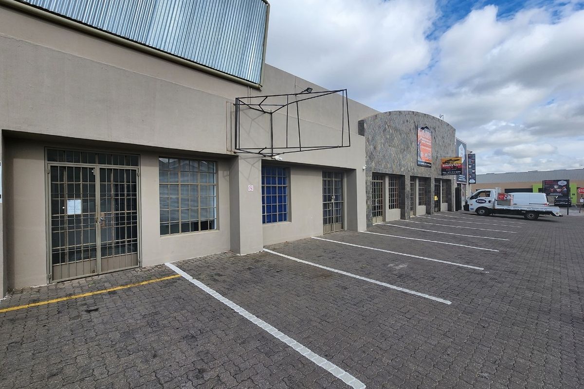 Front exterior view of a commercial property featuring paved parking, stone facade accents, and secure metal entrance gates.