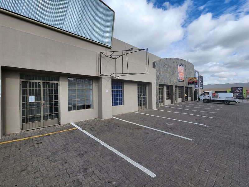 Front exterior view of a commercial property featuring paved parking, stone facade accents, and secure metal entrance gates.