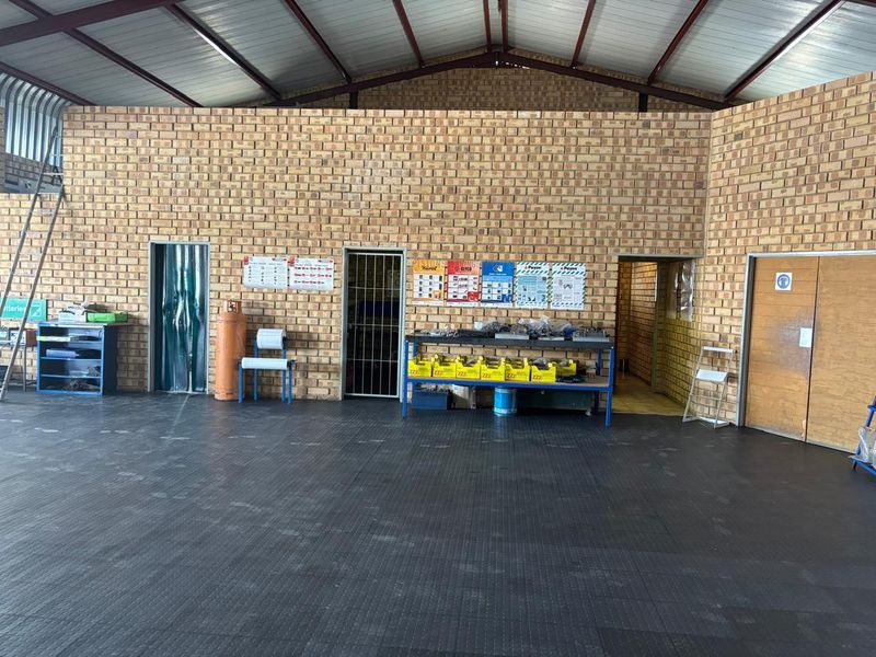 Spacious industrial utility area featuring exposed brick walls, durable rubberized flooring, and a high-clearance metal truss roof structure.