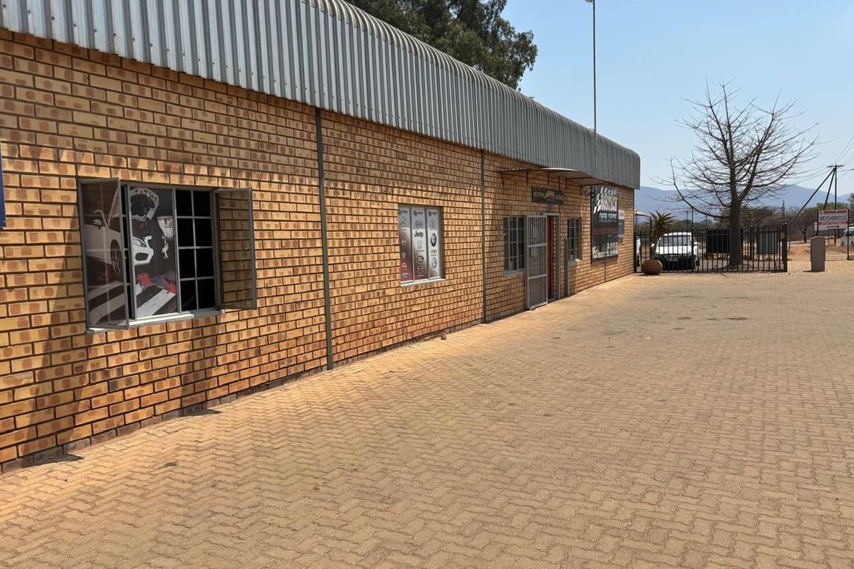 Industrial property exterior featuring a face brick facade, corrugated metal roofing, and a paved driveway entrance.