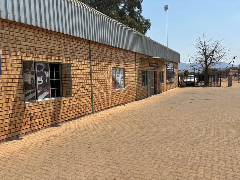Industrial property exterior featuring a face brick facade, corrugated metal roofing, and a paved driveway entrance.