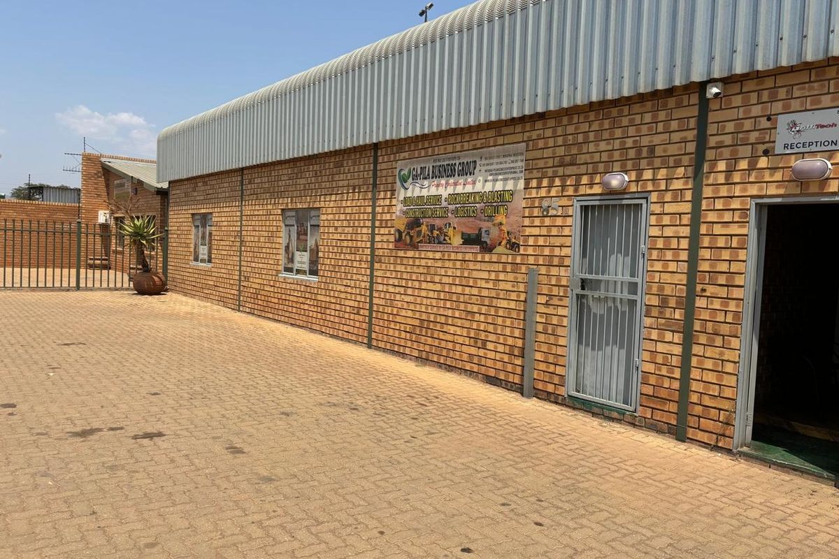 Industrial property exterior featuring a face brick facade, corrugated metal roofing, and a paved driveway with secure access points.