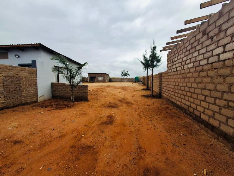 View of a commercial vacant land plot featuring perimeter brick walls and unfinished building structures under construction.