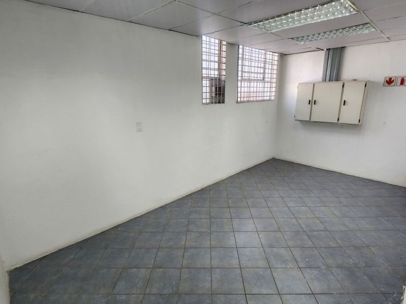 A functional, empty utility space featuring tiled flooring, suspended ceiling with integrated lighting, and wall-mounted storage cabinets.