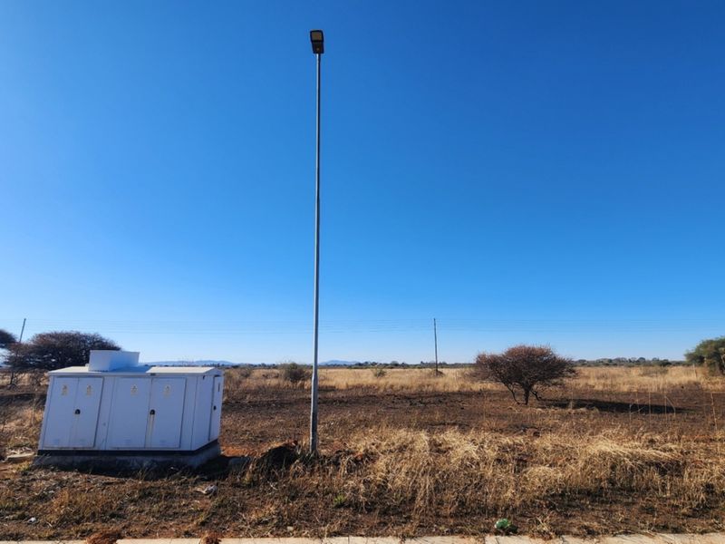 Vacant commercial land featuring an installed electrical transformer box and a street light pole on the property boundary.