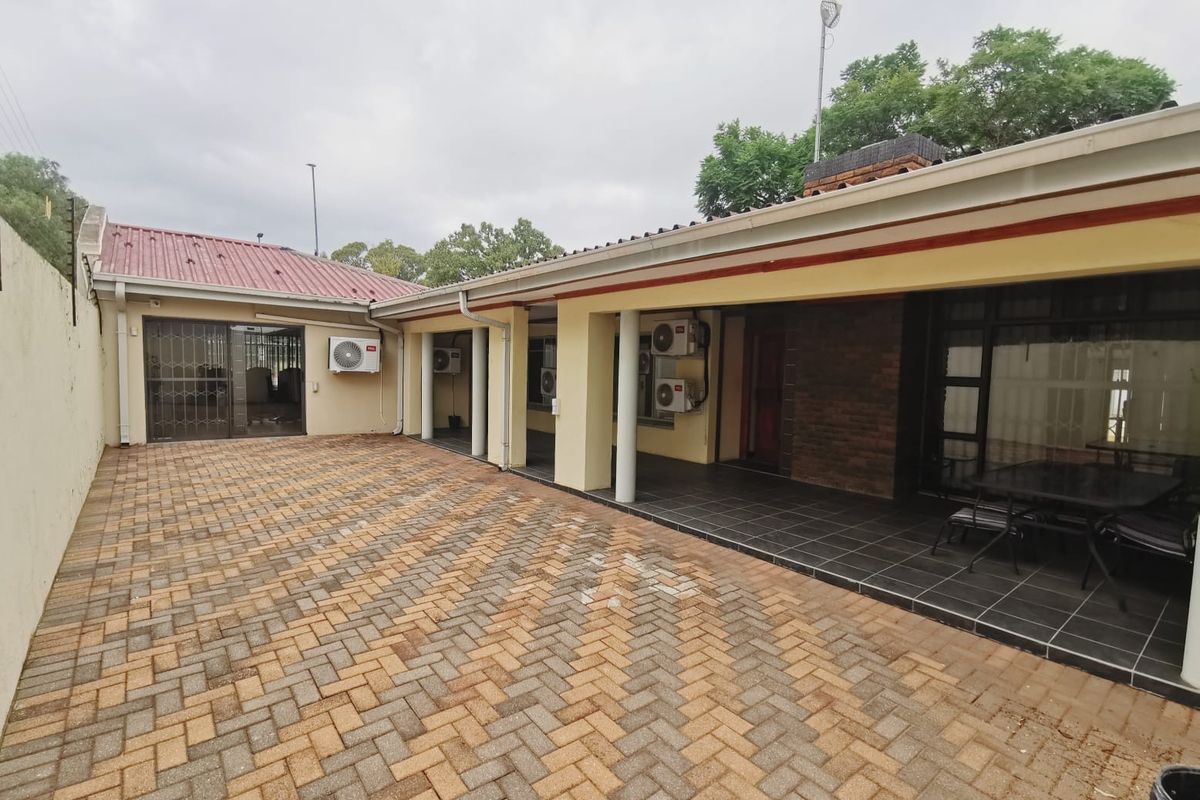 A paved rear courtyard featuring a covered patio area with multiple air conditioning units and secure access points to the office building.
