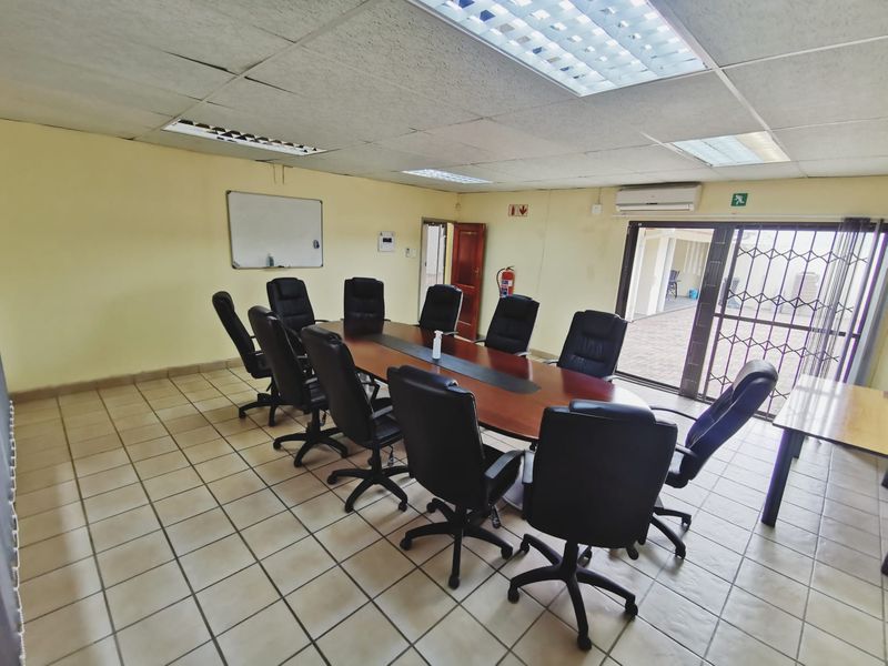 A functional office boardroom featuring ceramic tiled flooring, suspended ceiling with recessed lighting, and a wall-mounted air conditioning unit.