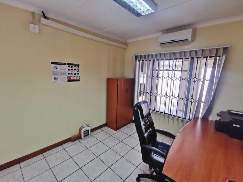 A functional office space featuring ceramic tiled flooring, a split-system air conditioner, and a security gate over the window.