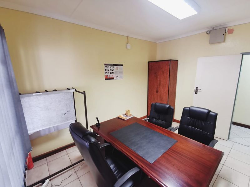 A functional office space featuring tiled flooring, built-in storage, and overhead fluorescent lighting, suitable for a professional work environment.